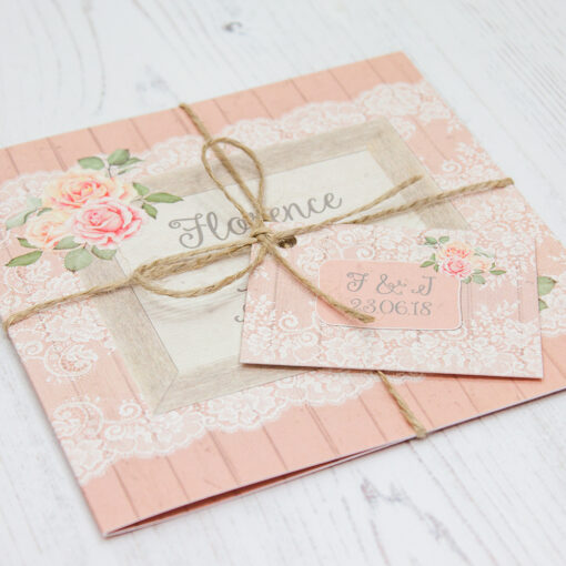 Close up of Folded Coral Haze Wedding Invitations with String & Tag